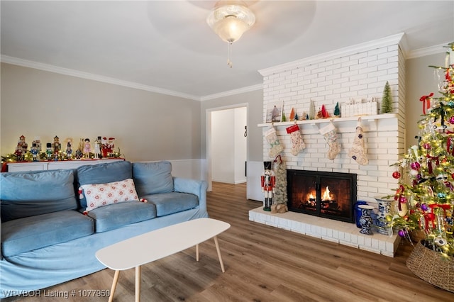 living room with crown molding, hardwood / wood-style floors, ceiling fan, and a brick fireplace