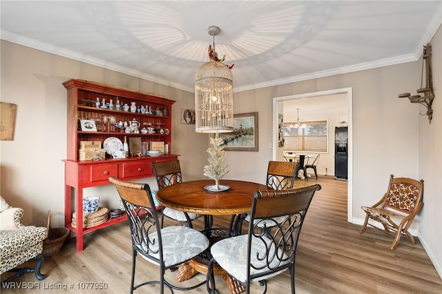 dining area with hardwood / wood-style flooring, crown molding, and an inviting chandelier