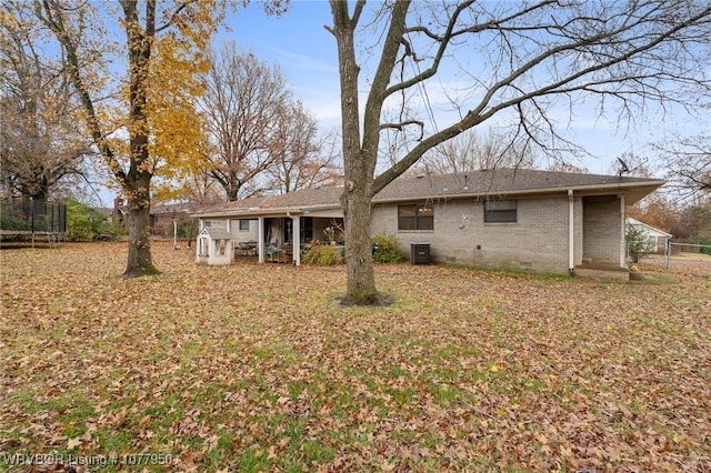 rear view of property featuring central AC unit and a trampoline