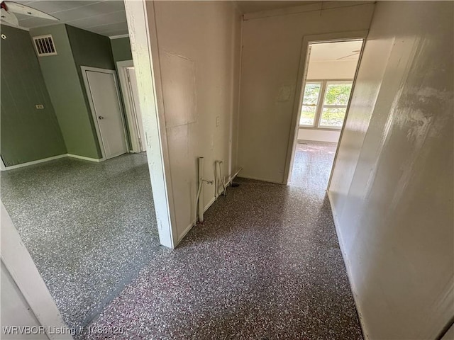 hallway with visible vents, baseboards, and speckled floor