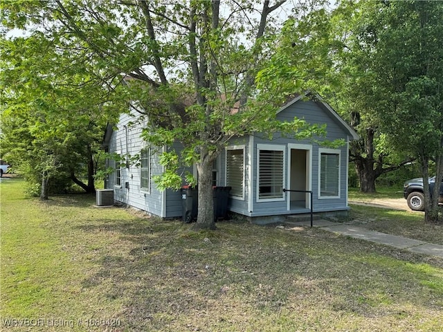 view of property exterior with a lawn and central air condition unit