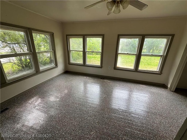 empty room featuring a wealth of natural light, baseboards, and ceiling fan