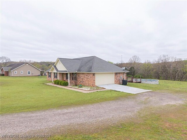 single story home with brick siding, a pool, a front lawn, an attached garage, and driveway