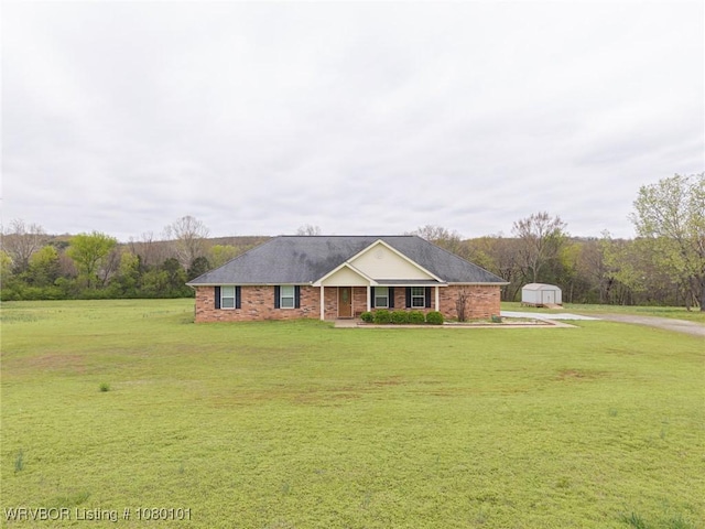 ranch-style home with an outdoor structure, driveway, a front lawn, brick siding, and a storage shed
