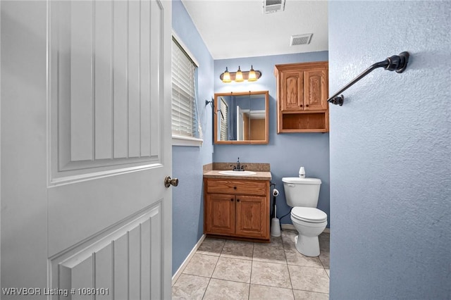 bathroom with toilet, vanity, tile patterned flooring, and visible vents