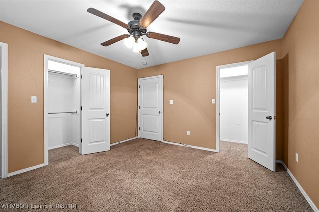 unfurnished bedroom with a closet, baseboards, a spacious closet, a ceiling fan, and carpet floors