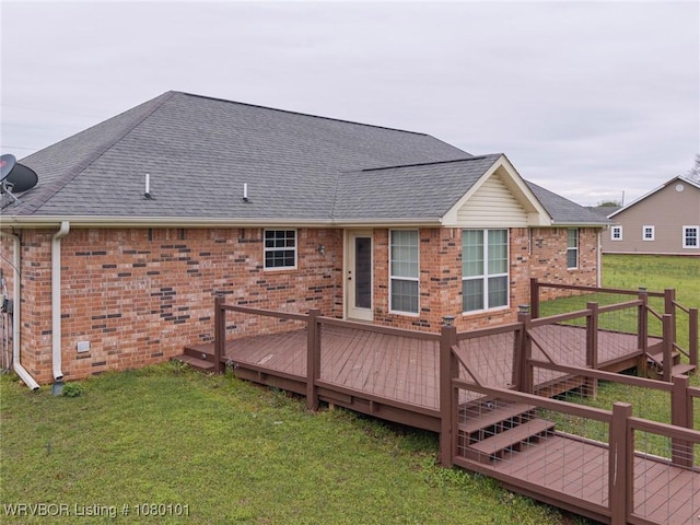 back of property featuring a yard, brick siding, a deck, and a shingled roof