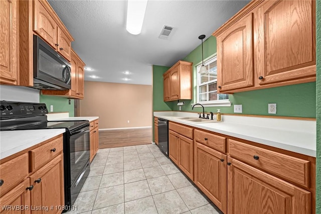 kitchen with visible vents, black appliances, light tile patterned flooring, light countertops, and a sink