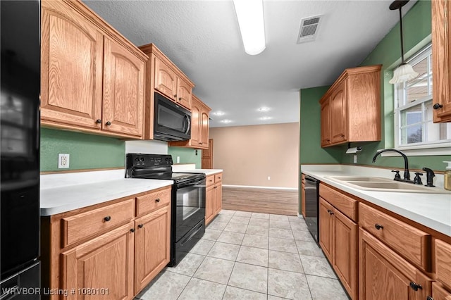 kitchen featuring light countertops, visible vents, a sink, and black appliances