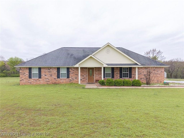 ranch-style home featuring brick siding, a front lawn, and roof with shingles