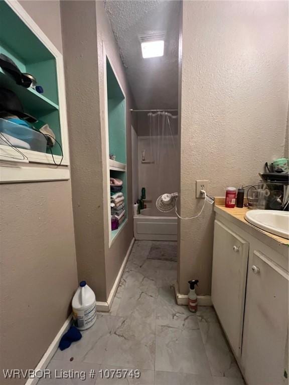 bathroom with vanity, a textured ceiling, and washtub / shower combination