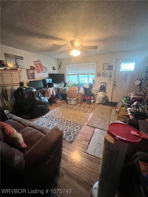 living room featuring ceiling fan, wood-type flooring, and a textured ceiling