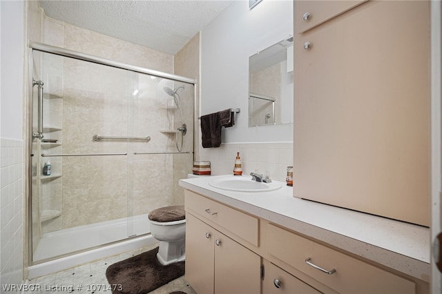 bathroom with an enclosed shower, a textured ceiling, vanity, tile walls, and toilet