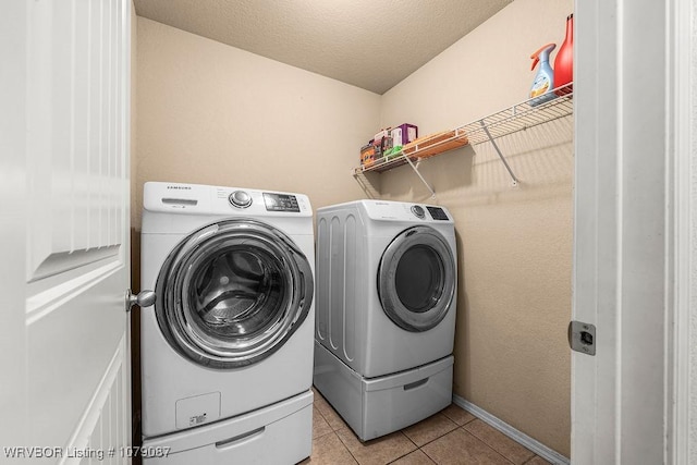 washroom featuring light tile patterned flooring, independent washer and dryer, and a textured ceiling