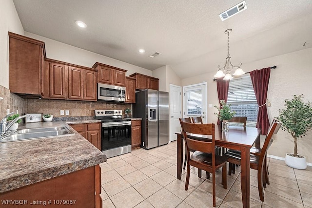 kitchen featuring a notable chandelier, sink, backsplash, appliances with stainless steel finishes, and pendant lighting