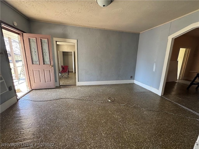 interior space featuring a textured ceiling, speckled floor, baseboards, and ornamental molding