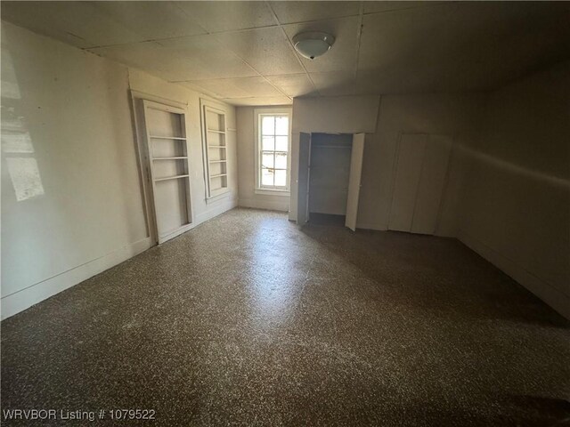 spare room with built in features, baseboards, and a drop ceiling