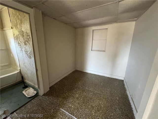 unfurnished room with baseboards and a drop ceiling