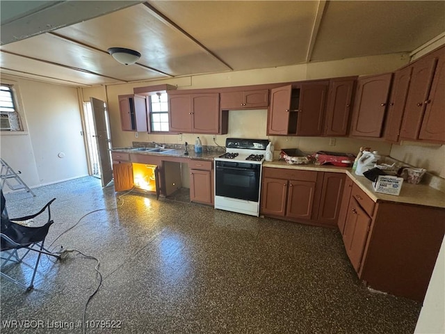 kitchen with gas range, light countertops, brown cabinets, and a sink