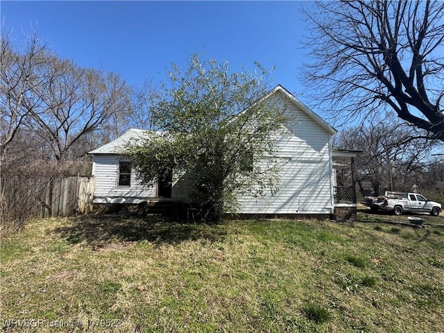 view of home's exterior featuring a lawn and fence