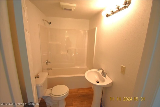 full bathroom with hardwood / wood-style flooring, toilet, shower / washtub combination, and sink