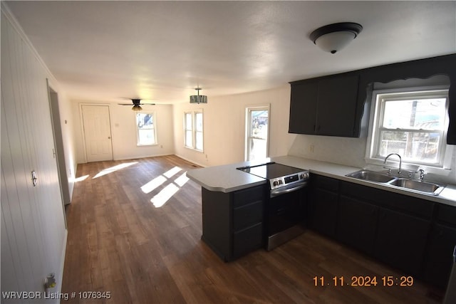 kitchen featuring kitchen peninsula, sink, dark wood-type flooring, and stainless steel range with electric stovetop