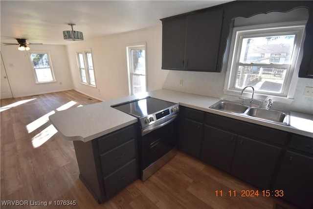 kitchen featuring kitchen peninsula, ceiling fan, dark wood-type flooring, sink, and electric stove