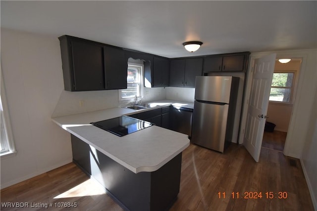 kitchen with kitchen peninsula, stainless steel fridge, sink, and dark hardwood / wood-style floors