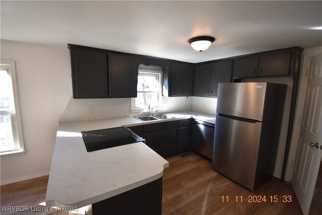 kitchen with kitchen peninsula, appliances with stainless steel finishes, dark hardwood / wood-style flooring, and sink