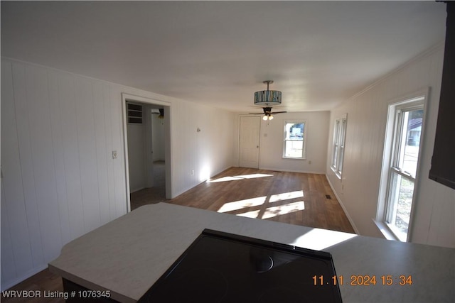 interior space with ceiling fan, hardwood / wood-style floors, and wooden walls