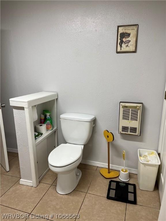 bathroom featuring toilet, heating unit, and tile patterned floors