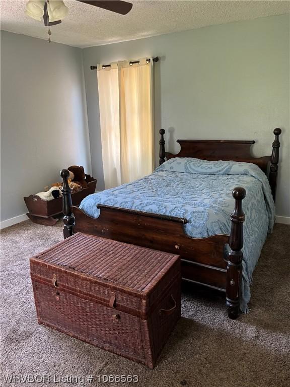 carpeted bedroom featuring ceiling fan and a textured ceiling