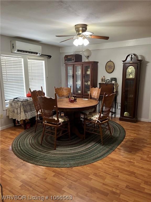 dining space with ceiling fan, light wood-type flooring, and a wall unit AC