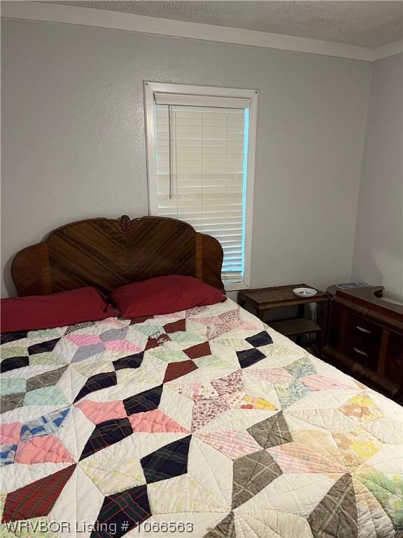 bedroom with ornamental molding and a textured ceiling