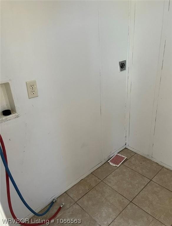 laundry area with hookup for an electric dryer and light tile patterned floors