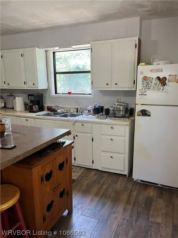 kitchen with white cabinets, white refrigerator, dark hardwood / wood-style flooring, and sink