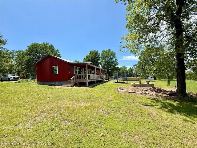 12878 128th St, Gore, OK 74435 - view of green lawn with a trampoline and a deck