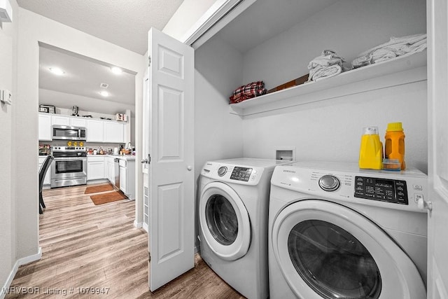 clothes washing area featuring a textured ceiling, laundry area, separate washer and dryer, and light wood finished floors