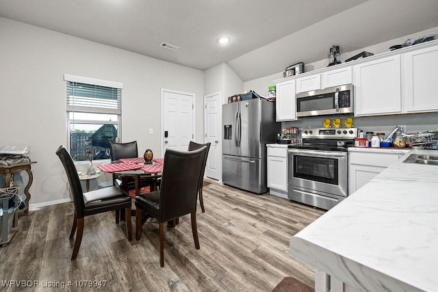 kitchen featuring white cabinets, visible vents, baseboards, appliances with stainless steel finishes, and light wood-type flooring