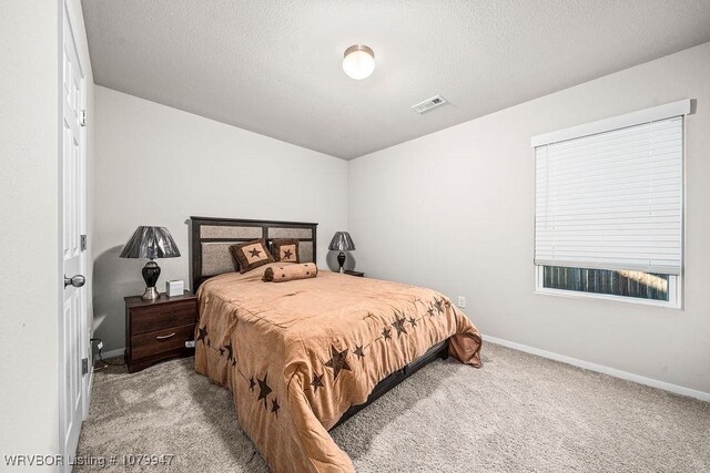 carpeted bedroom featuring a textured ceiling, baseboards, and visible vents