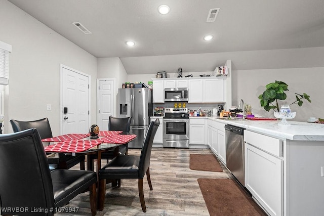 kitchen featuring a sink, visible vents, white cabinets, appliances with stainless steel finishes, and wood finished floors