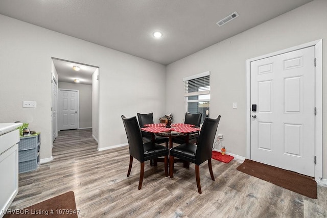 dining room with baseboards, light wood finished floors, and visible vents