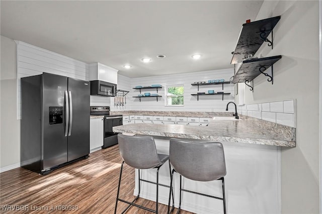 1003 Blair St, Pocola, OK 74902 - kitchen with stainless steel appliances, open shelves, a sink, a peninsula, and wood finished floors