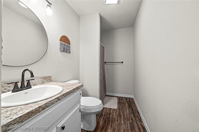 1003 Blair St, Pocola, OK 74902 - full bath featuring wood finished floors, vanity, toilet, a shower with shower curtain, and baseboards