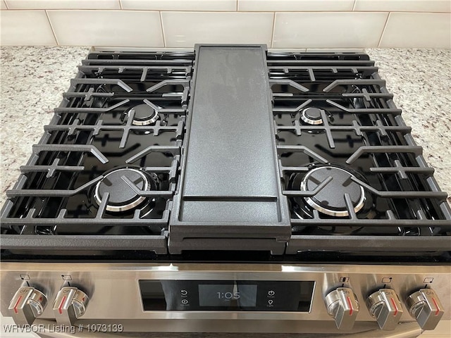 details with stainless steel gas stove and light stone countertops