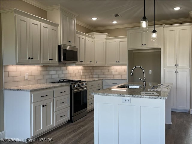 kitchen with decorative light fixtures, white cabinetry, stainless steel appliances, and an island with sink