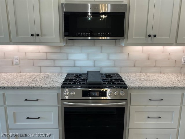 kitchen with white cabinets, appliances with stainless steel finishes, and tasteful backsplash