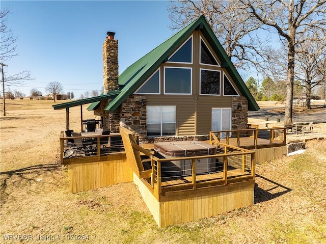 back of house with a deck, metal roof, and a chimney