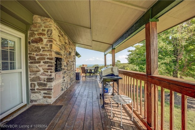 wooden deck with a stone fireplace and grilling area