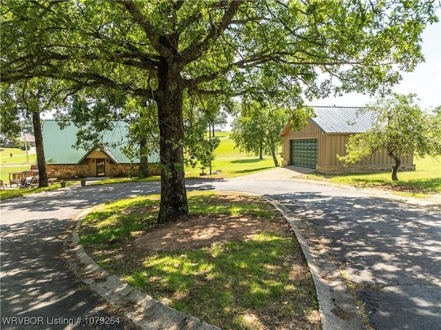 view of front facade featuring a garage, a front yard, metal roof, and an outdoor structure